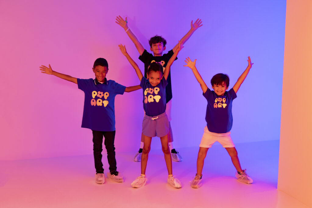 four kids standing close to each other with their arms up