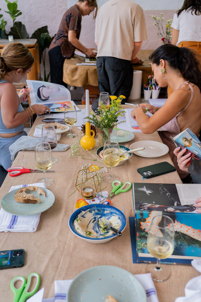 Dos mujeres sentadas una frente a la otra cortando revistas