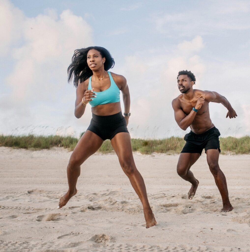 a man and a woman running on the beach.